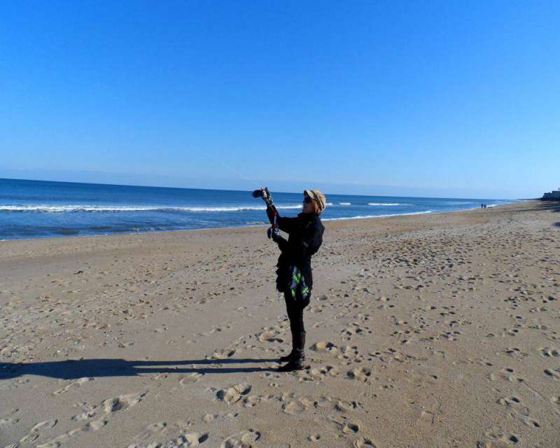 woman at the beach in winter flying a kite