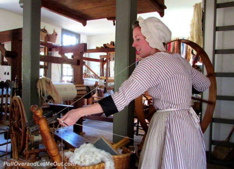 A costumed interpreter working with a spinning wheel in Colonial Williamsburg